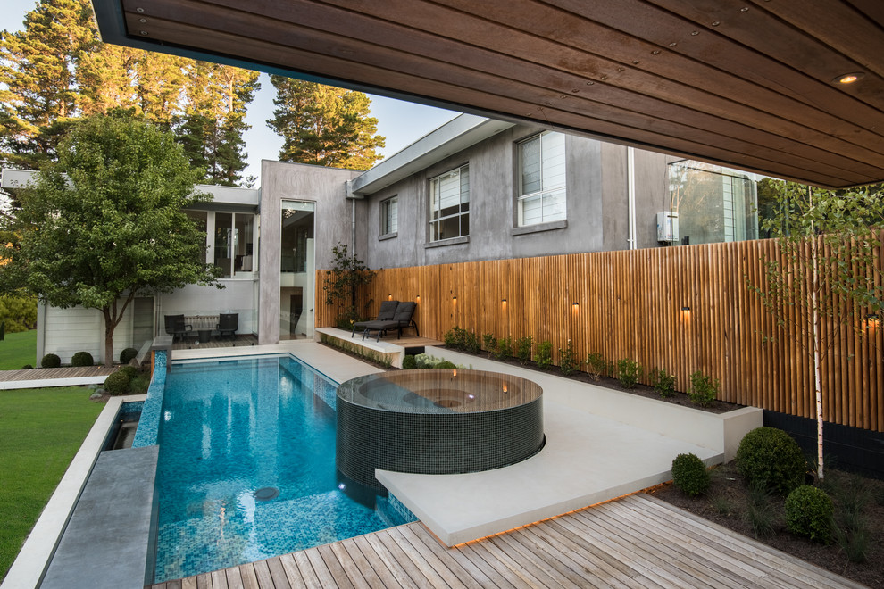 Идея дизайна: большой бассейн-инфинити произвольной формы на заднем дворе в современном стиле с джакузи и покрытием из бетонных плит