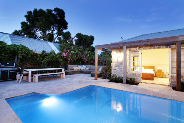 Ejemplo de casa de la piscina y piscina elevada marinera de tamaño medio rectangular en patio trasero con suelo de baldosas