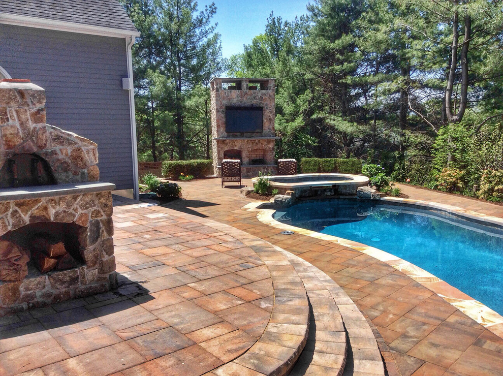 Example of a mid-sized transitional backyard concrete paver and custom-shaped natural pool design in New York