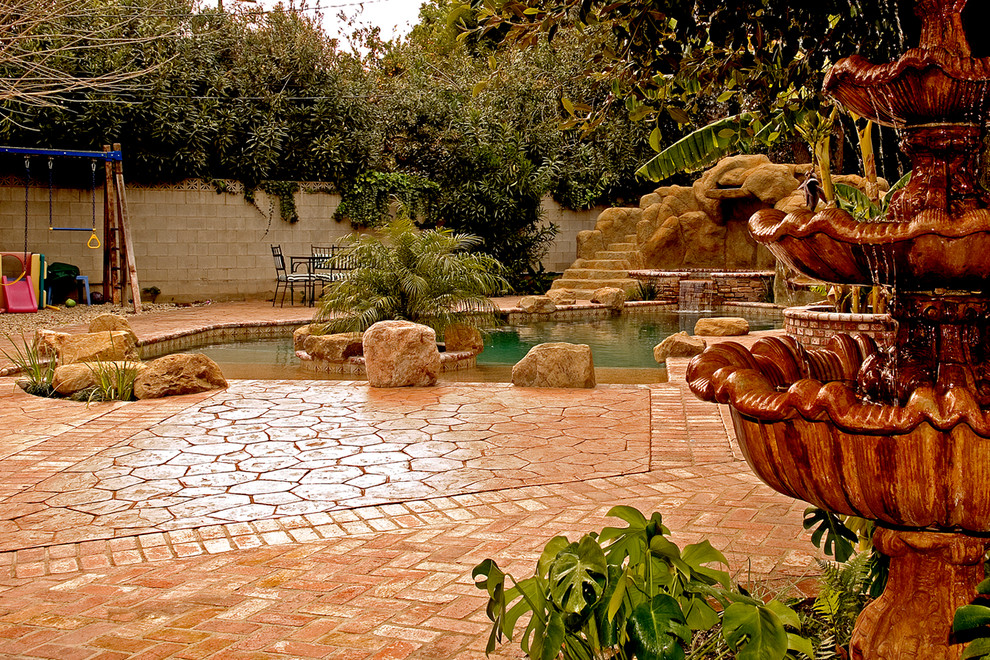 Imagen de piscina con tobogán clásica renovada de tamaño medio a medida en patio trasero con adoquines de ladrillo
