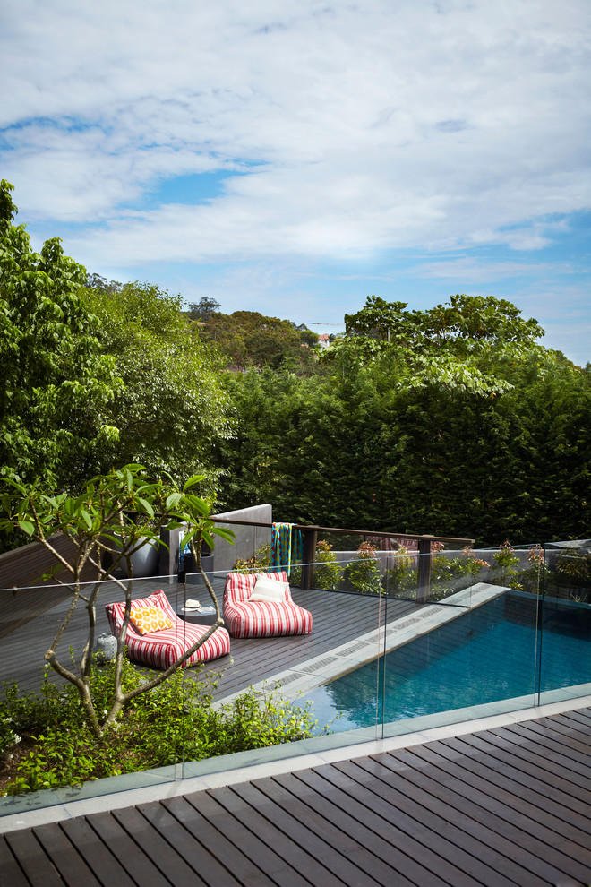 Esempio di un'ampia piscina a sfioro infinito minimal personalizzata dietro casa con fontane