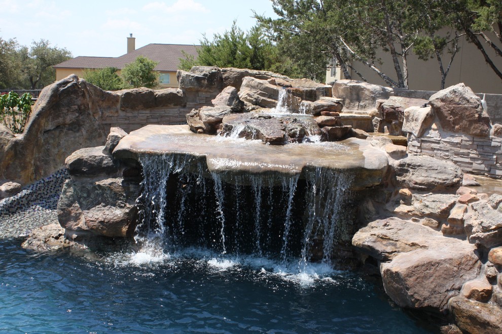Ejemplo de piscina con fuente natural rústica de tamaño medio a medida en patio trasero con adoquines de ladrillo