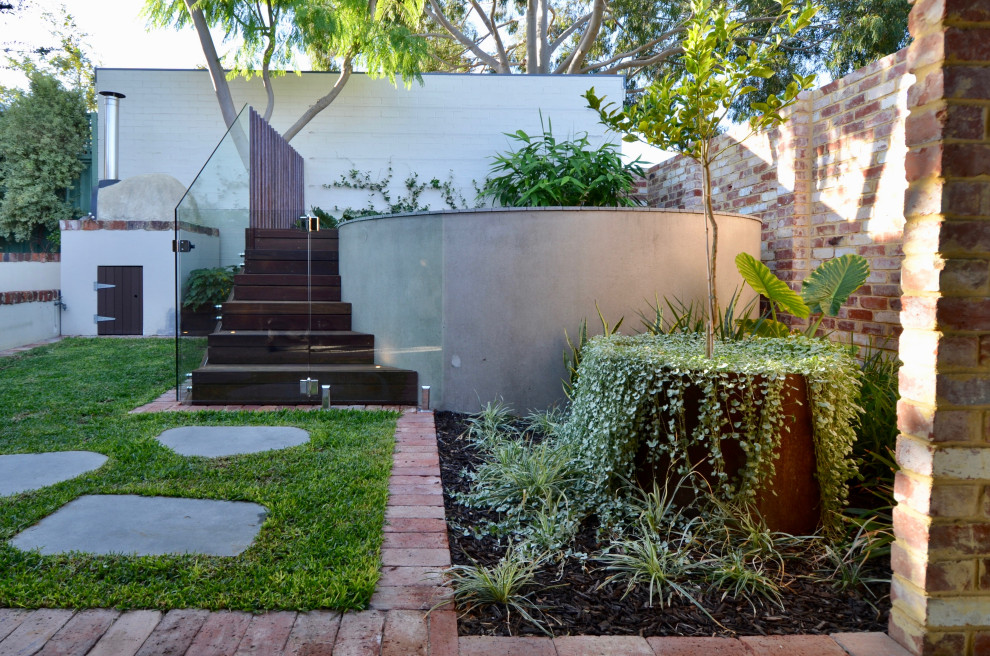 Foto de piscina elevada moderna pequeña redondeada en patio trasero con adoquines de ladrillo y paisajismo de piscina