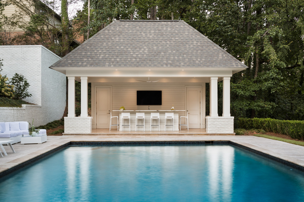 Ejemplo de casa de la piscina y piscina actual grande rectangular en patio trasero con adoquines de piedra natural