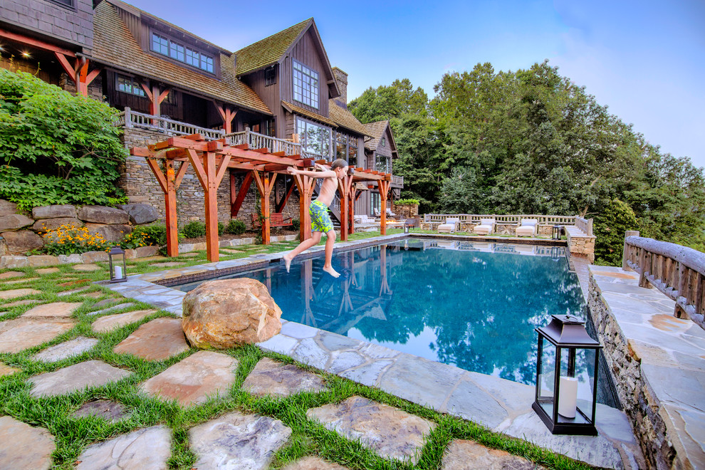Esempio di una grande piscina a sfioro infinito rustica rettangolare dietro casa con pavimentazioni in pietra naturale