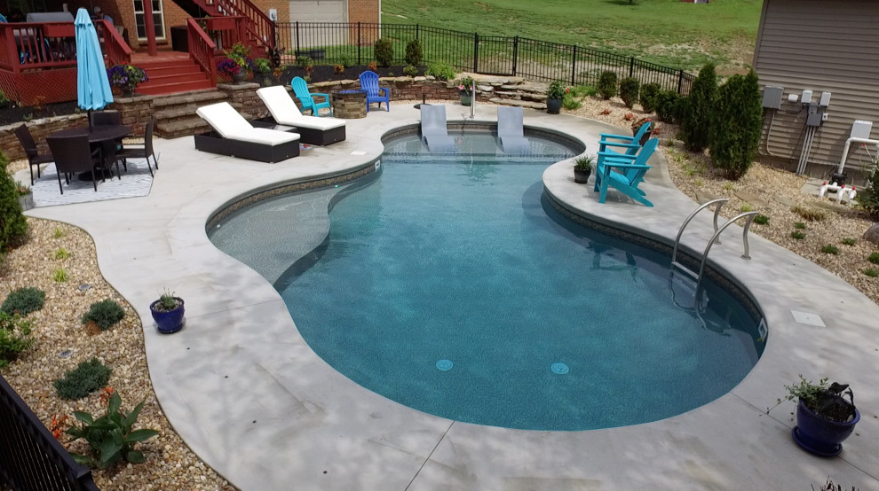 Ejemplo de piscina tropical de tamaño medio a medida en patio trasero con losas de hormigón