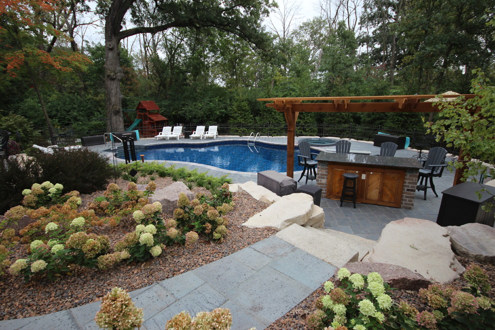 Ejemplo de piscinas y jacuzzis alargados mediterráneos de tamaño medio tipo riñón en patio trasero con adoquines de piedra natural