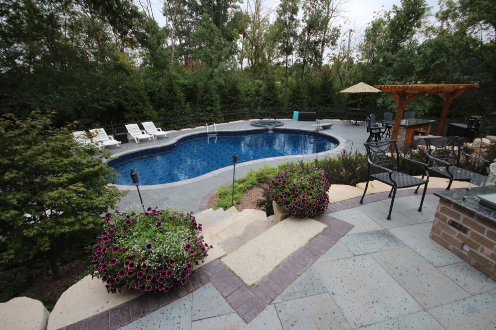 Ejemplo de piscinas y jacuzzis alargados mediterráneos de tamaño medio tipo riñón en patio trasero con adoquines de piedra natural