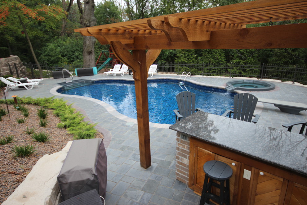 Esempio di una piscina monocorsia mediterranea a "C" di medie dimensioni e dietro casa con una vasca idromassaggio e pavimentazioni in pietra naturale