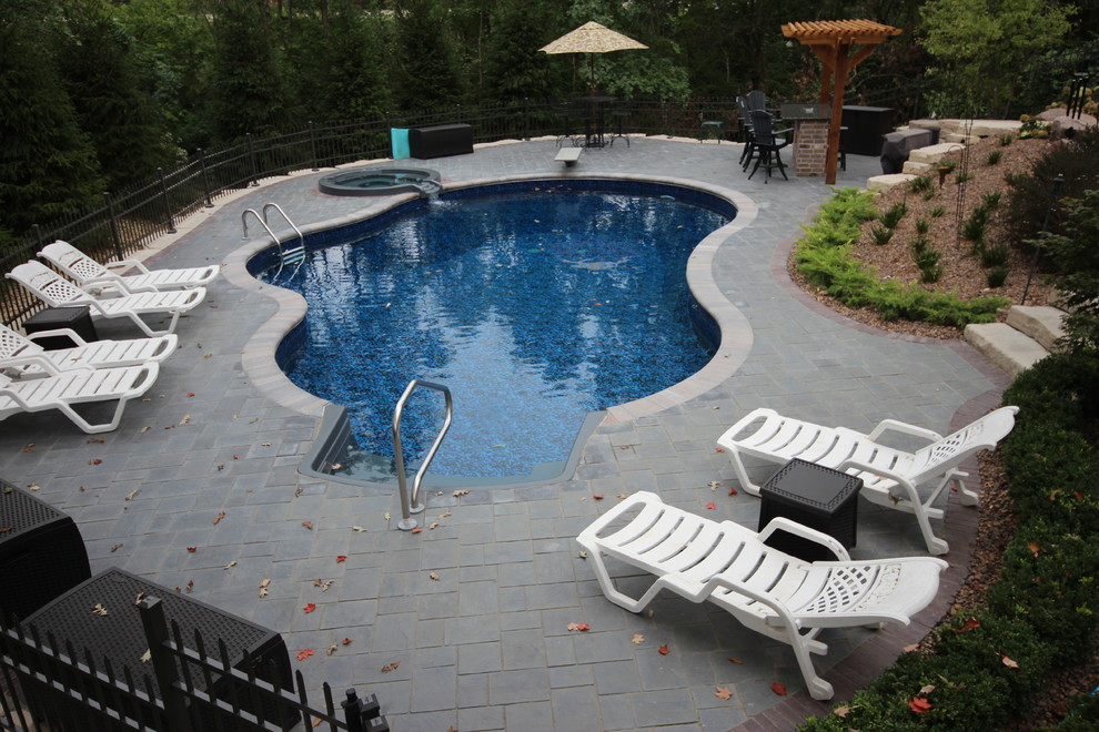 Example of a mid-sized tuscan backyard stone and kidney-shaped lap hot tub design in Chicago