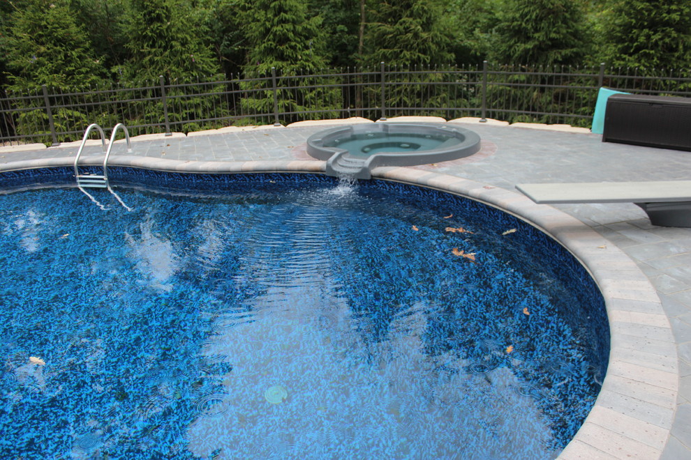 Esempio di una piscina monocorsia mediterranea a "C" di medie dimensioni e dietro casa con una vasca idromassaggio e pavimentazioni in pietra naturale