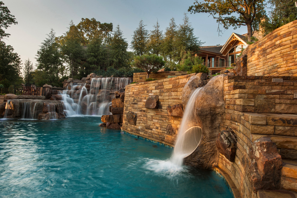 Ispirazione per un'ampia piscina naturale stile rurale personalizzata dietro casa con un acquascivolo e pavimentazioni in pietra naturale