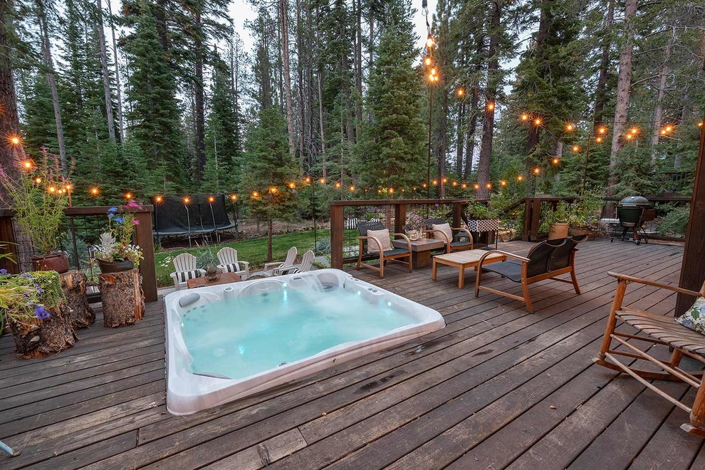 Example of a mountain style backyard hot tub design in Sacramento with decking