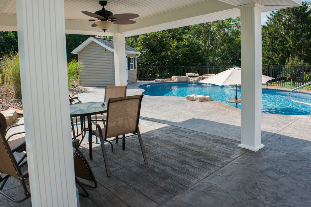 Ejemplo de piscina con fuente natural romántica de tamaño medio a medida en patio trasero con suelo de hormigón estampado