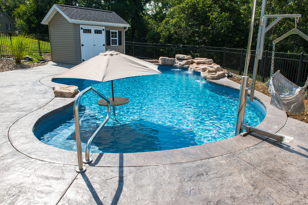 Immagine di una piscina naturale shabby-chic style personalizzata di medie dimensioni e dietro casa con fontane e cemento stampato