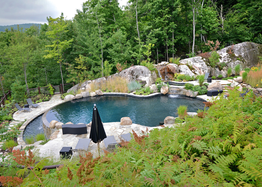 Esempio di un'ampia piscina a sfioro infinito stile rurale personalizzata dietro casa con fontane e pavimentazioni in pietra naturale
