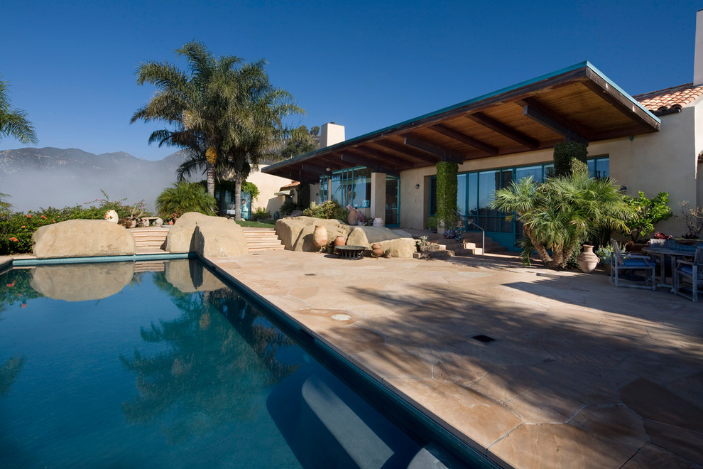 Ejemplo de piscina con fuente de estilo americano grande en patio trasero con adoquines de piedra natural