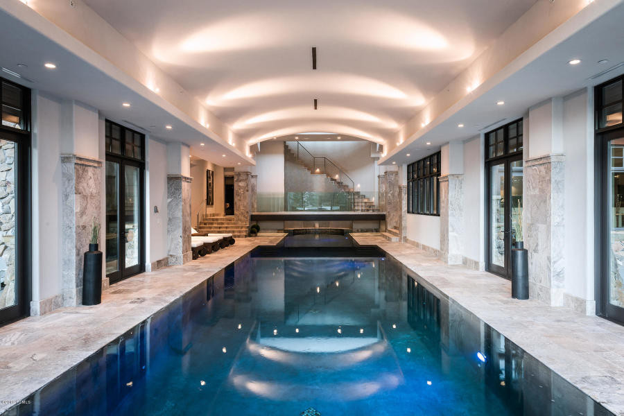 This is an example of an expansive classic indoor rectangular swimming pool in Salt Lake City with a pool house and natural stone paving.