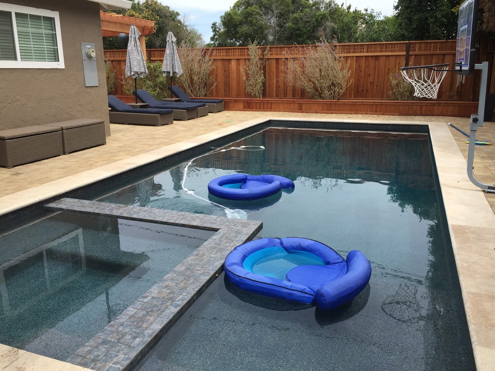 Ispirazione per una grande piscina monocorsia minimalista rettangolare dietro casa con pavimentazioni in cemento e una vasca idromassaggio