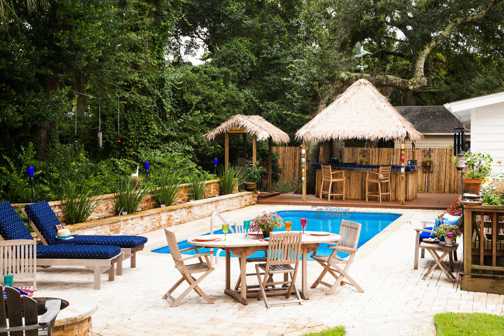 Idee per una piscina tropicale dietro casa con pavimentazioni in pietra naturale