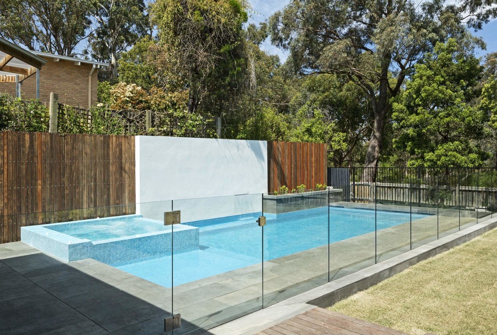 Exemple d'une piscine arrière tendance de taille moyenne et sur mesure avec un bain bouillonnant et des pavés en béton.
