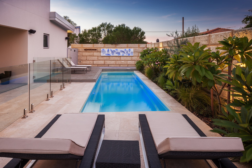 Immagine di una piscina stile marino rettangolare di medie dimensioni e dietro casa con pavimentazioni in pietra naturale