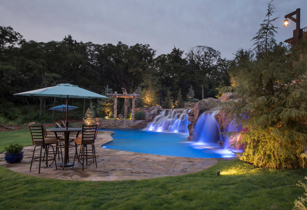 Ispirazione per un'ampia piscina naturale tradizionale personalizzata dietro casa con fontane e pavimentazioni in pietra naturale
