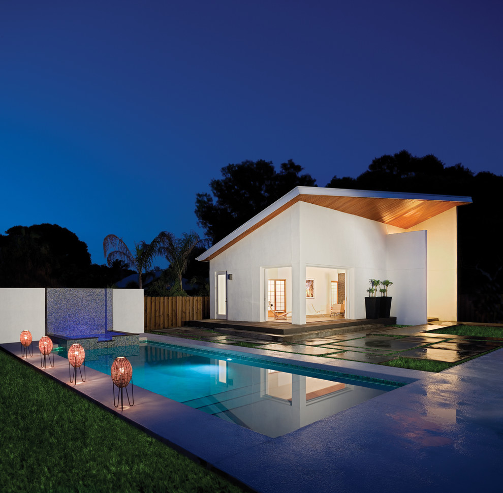 Foto på en liten funkis pool på baksidan av huset, med betongplatta och poolhus