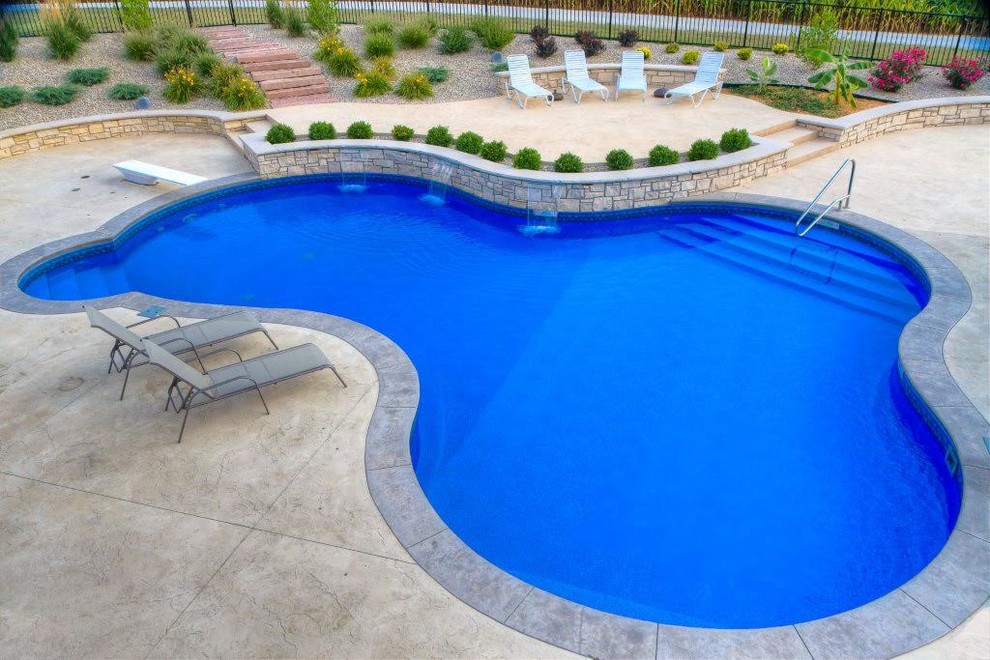 Diseño de piscina con fuente alargada tradicional renovada de tamaño medio a medida en patio trasero con adoquines de hormigón