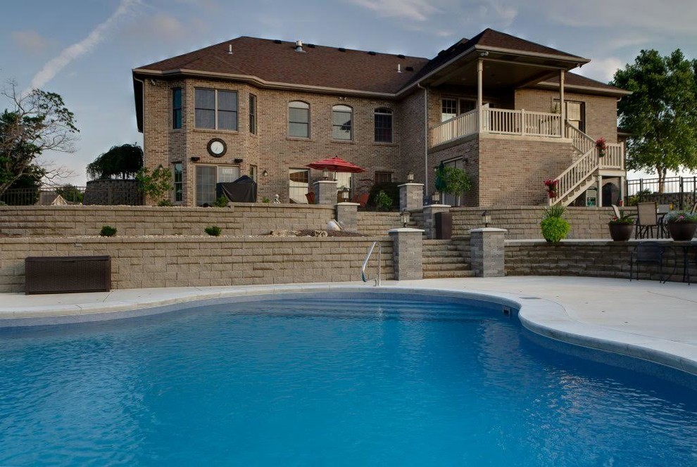 Imagen de piscina alargada tradicional renovada de tamaño medio a medida en patio trasero con adoquines de hormigón