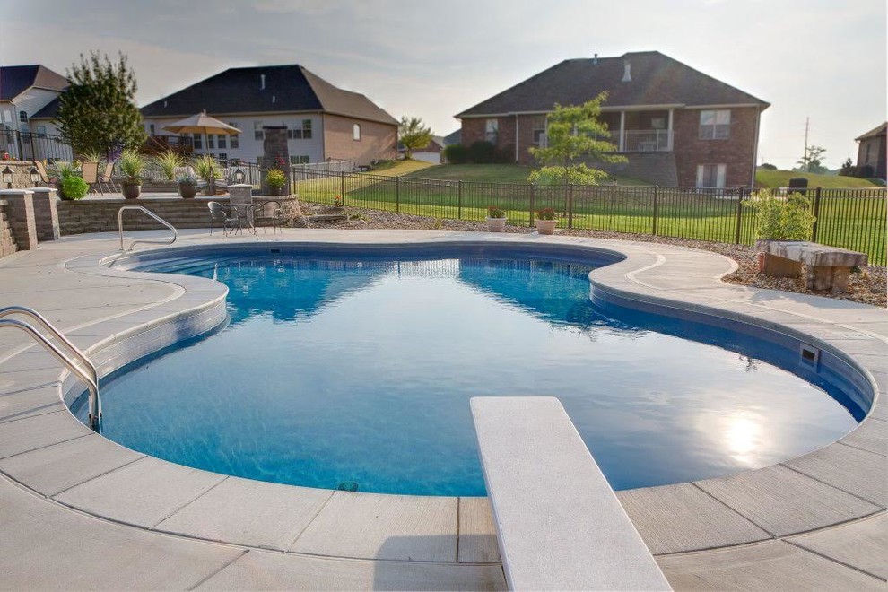 Ejemplo de piscina alargada tradicional renovada de tamaño medio a medida en patio trasero con adoquines de hormigón
