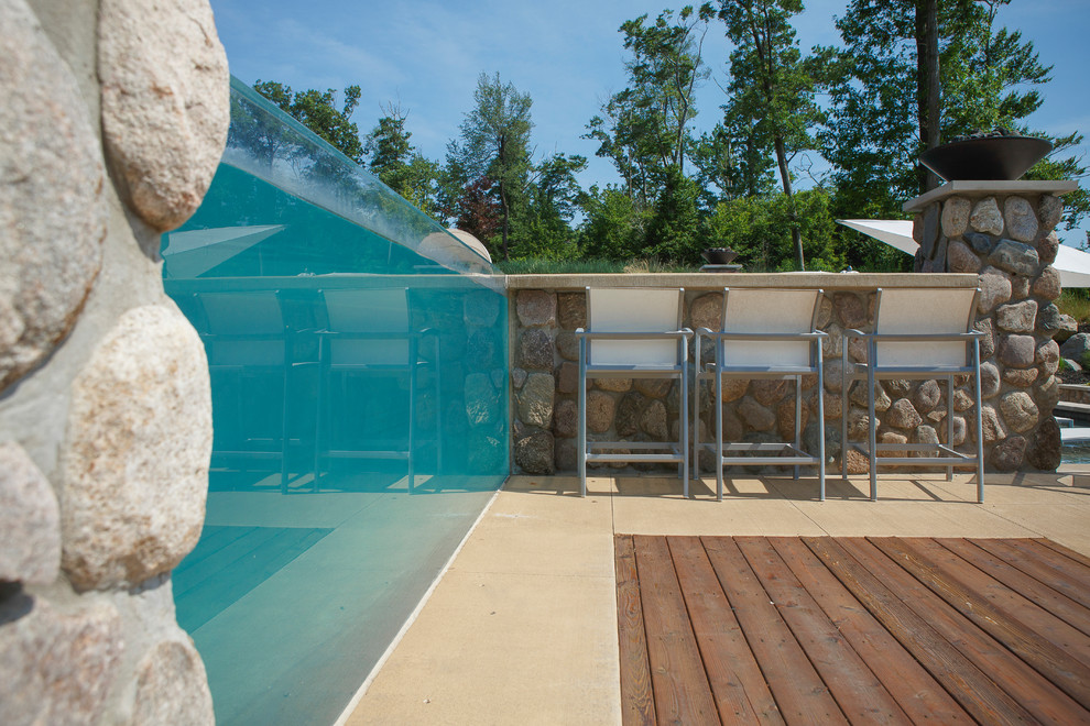 Example of a huge minimalist backyard stone and custom-shaped infinity pool fountain design in Grand Rapids