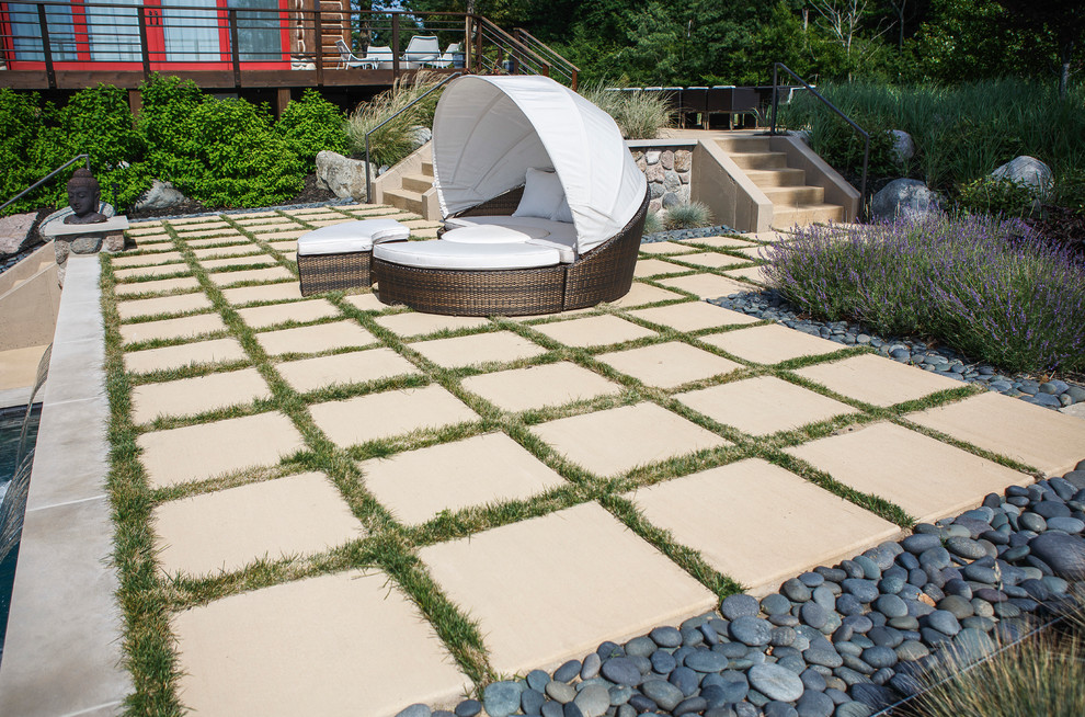 Foto di un'ampia piscina a sfioro infinito minimalista personalizzata dietro casa con fontane e pavimentazioni in pietra naturale