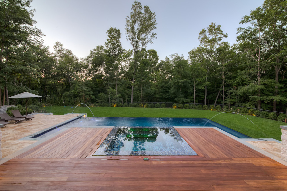 Diseño de piscinas y jacuzzis infinitos grandes rectangulares en patio trasero con adoquines de piedra natural
