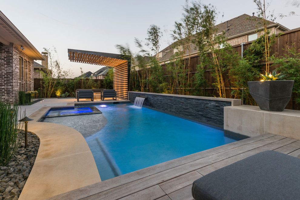 Imagen de piscina actual pequeña rectangular en patio trasero con losas de hormigón