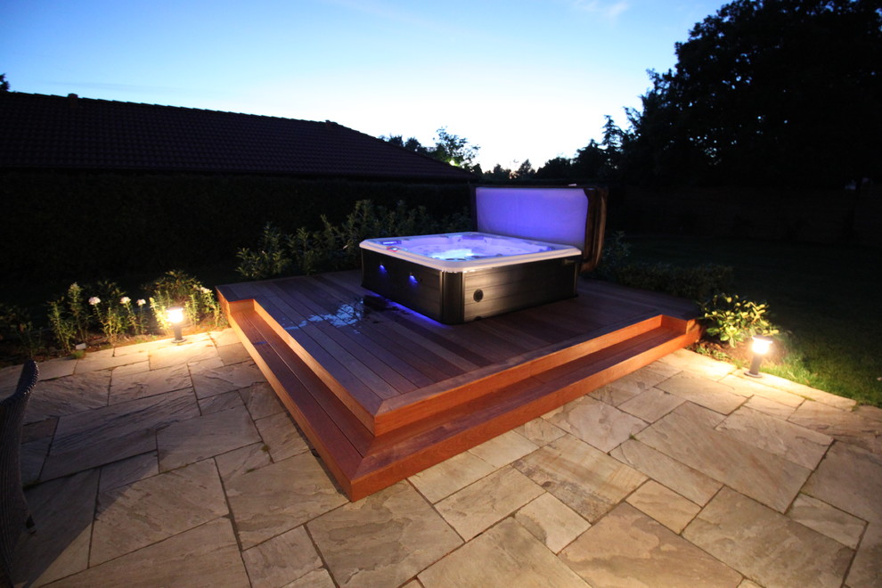 Cette photo montre une piscine arrière moderne avec un bain bouillonnant et une terrasse en bois.
