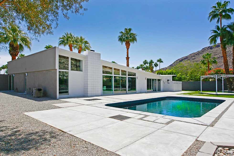 Foto de piscina retro de tamaño medio rectangular en patio trasero con losas de hormigón