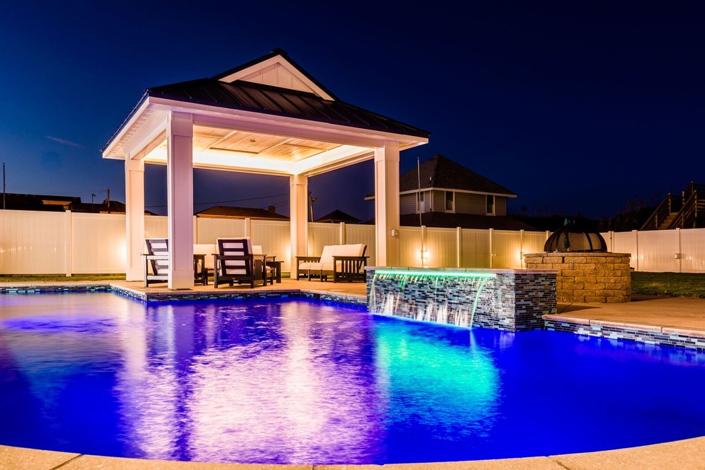 Diseño de piscina con fuente alargada tradicional de tamaño medio rectangular en patio trasero con losas de hormigón