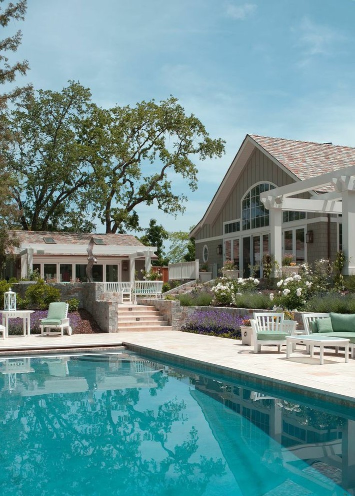 Diseño de piscina con fuente campestre grande en patio trasero con adoquines de piedra natural