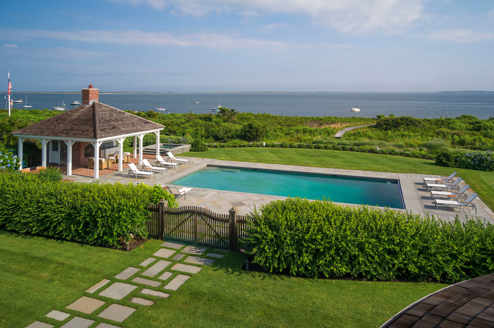 Modelo de casa de la piscina y piscina alargada costera grande rectangular en patio trasero con adoquines de piedra natural