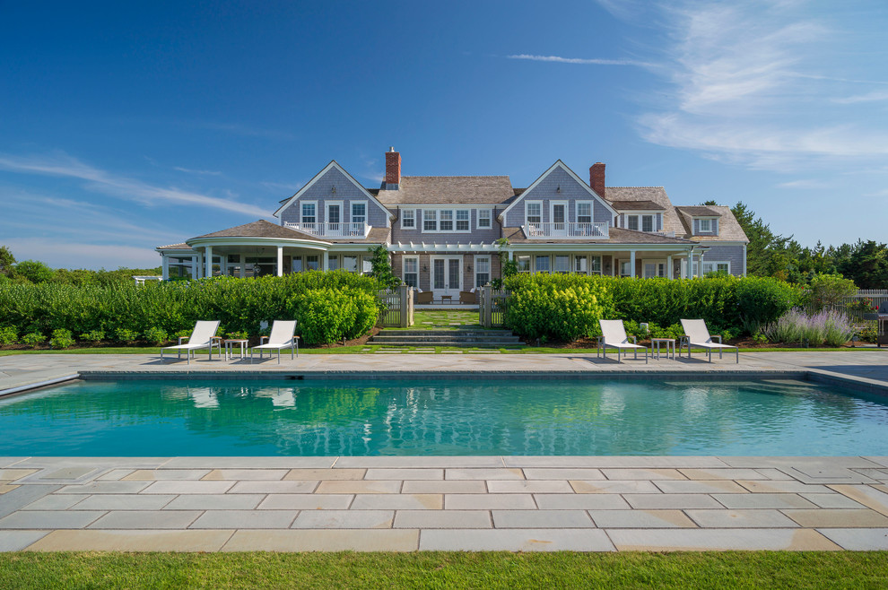 Cette photo montre une grande piscine arrière bord de mer rectangle avec des pavés en pierre naturelle.