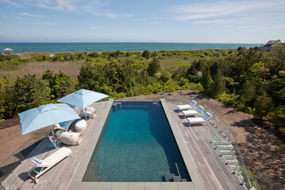 Imagen de piscina infinita marinera rectangular en patio trasero con entablado
