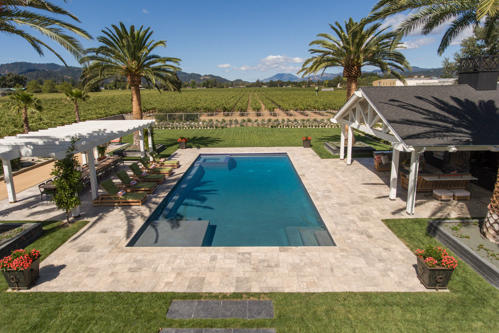 Ejemplo de casa de la piscina y piscina de estilo de casa de campo de tamaño medio rectangular en patio trasero con adoquines de piedra natural