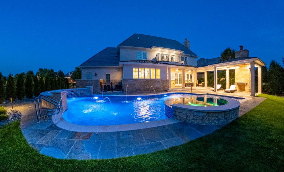 Diseño de piscina natural moderna de tamaño medio a medida en patio trasero con paisajismo de piscina y adoquines de piedra natural