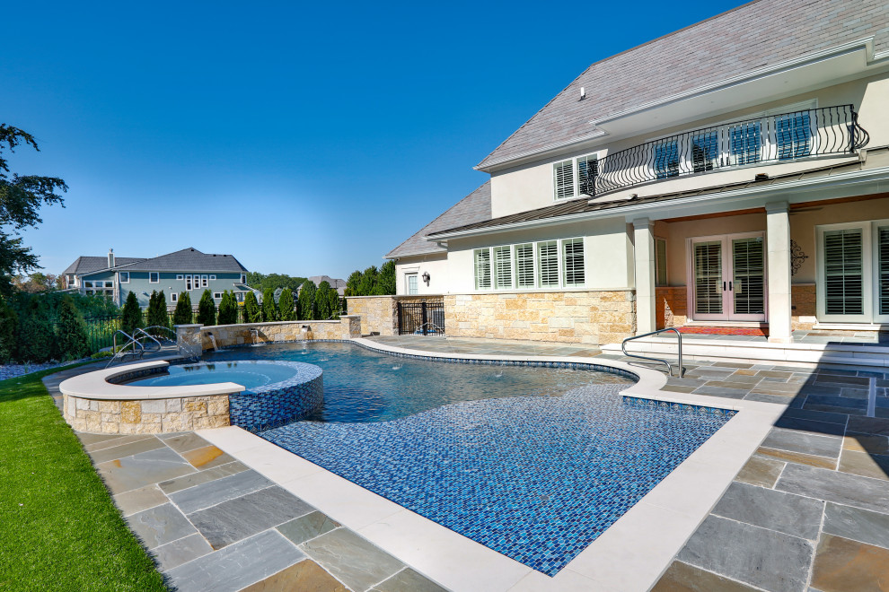 This is an example of a medium sized modern back custom shaped natural swimming pool in Chicago with with pool landscaping and natural stone paving.