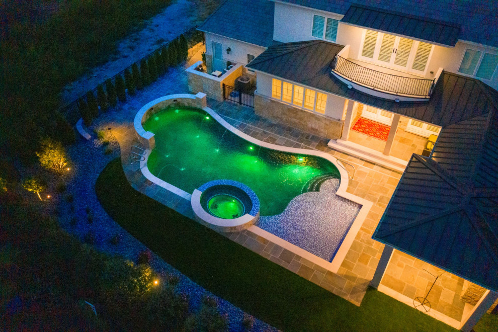 Medium sized modern back custom shaped natural swimming pool in Chicago with with pool landscaping and natural stone paving.