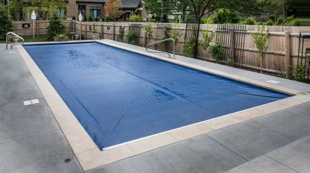 Imagen de piscina con fuente alargada clásica de tamaño medio rectangular en patio trasero con losas de hormigón
