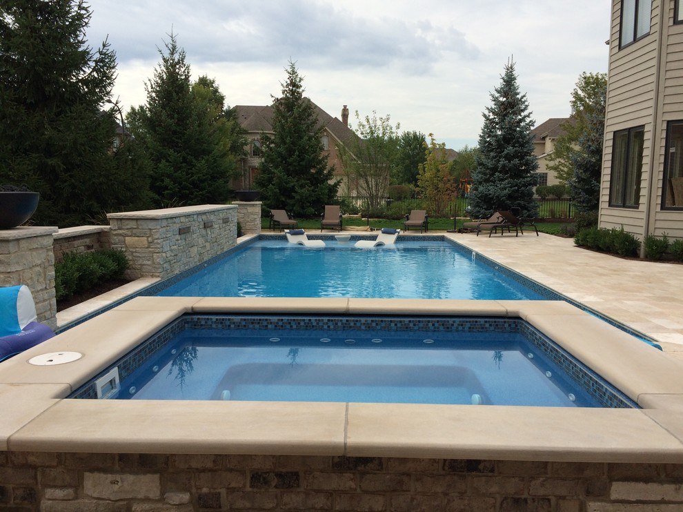 Ejemplo de piscinas y jacuzzis alargados tradicionales grandes rectangulares en patio trasero con adoquines de piedra natural