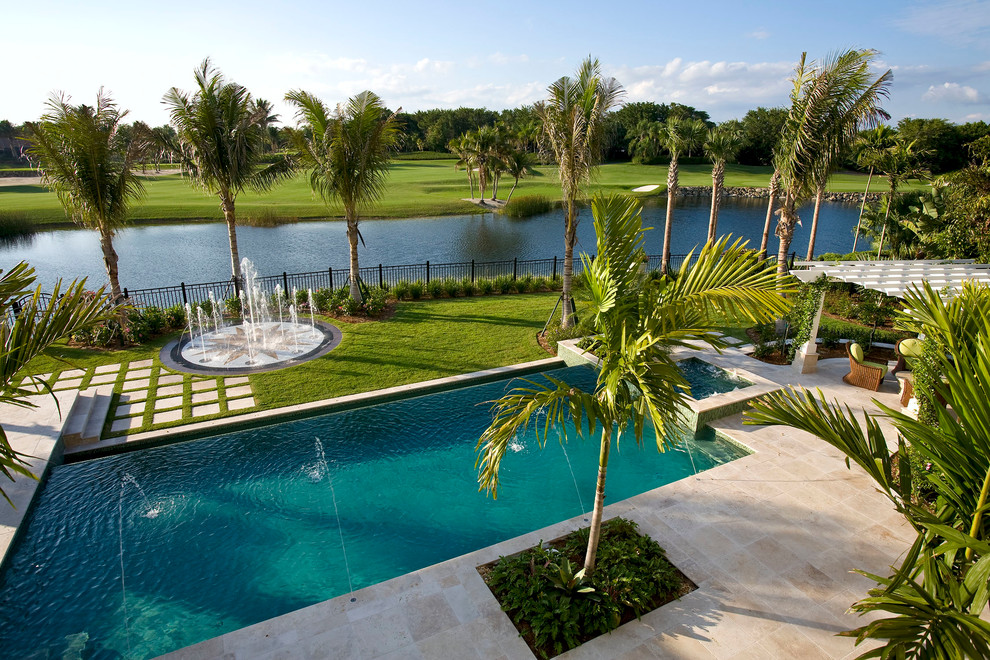 Foto di una piscina a sfioro infinito tropicale rettangolare di medie dimensioni e dietro casa con fontane e ghiaia