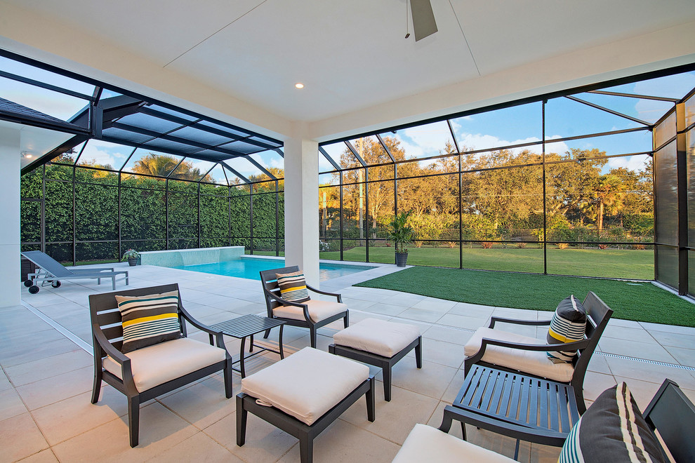 Diseño de piscina con fuente alargada tropical grande rectangular en patio trasero con adoquines de hormigón